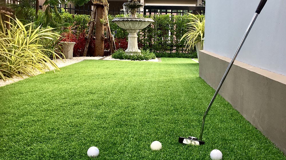 Putter and 3 golf balls on artificial grass