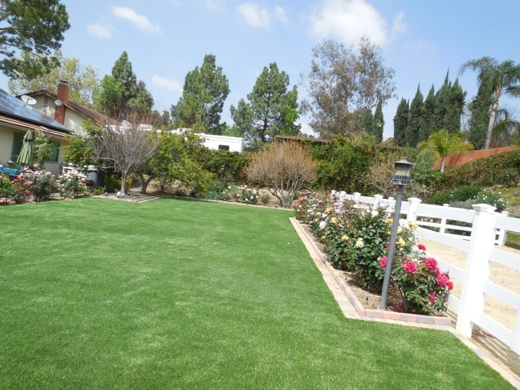 Artificial grass backyard with white fence