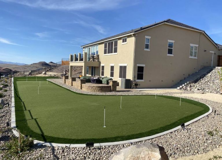 Backyard putting green next to tan house from Nevada Artificial Grass